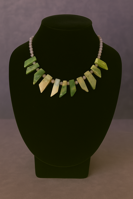 Necklace with green and beige beads on a black mannequin bust against a gray background