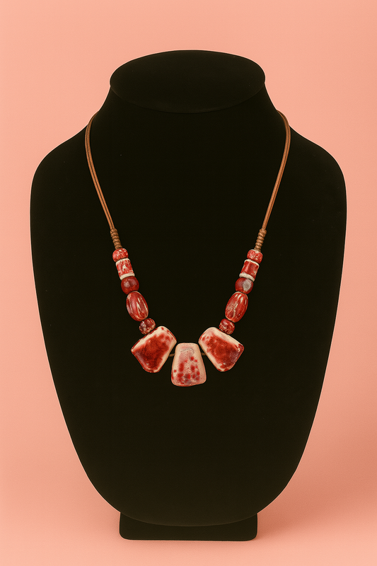 Necklace with red and white beads on a black mannequin bust against a pink background