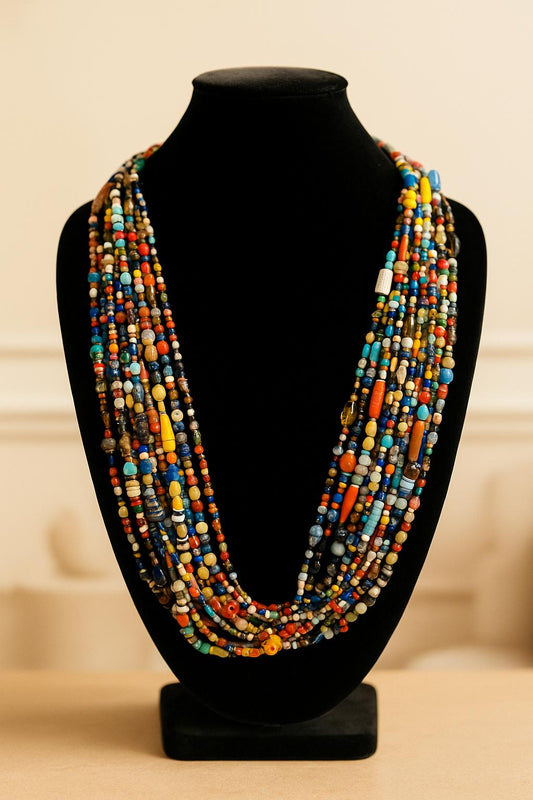 Colorful beaded necklace on a black mannequin bust against a beige background