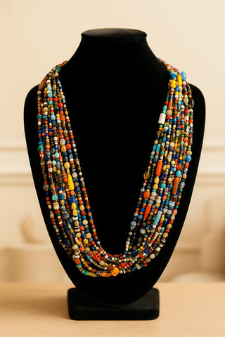 Colorful beaded necklace on a black mannequin bust against a beige background