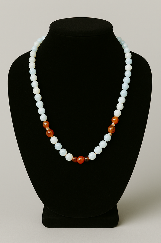 Necklace with white and orange beads on a black mannequin bust against a gray background