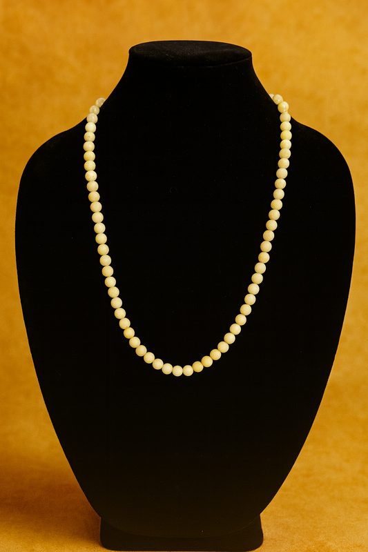 Pearl necklace on a black mannequin bust against an orange background