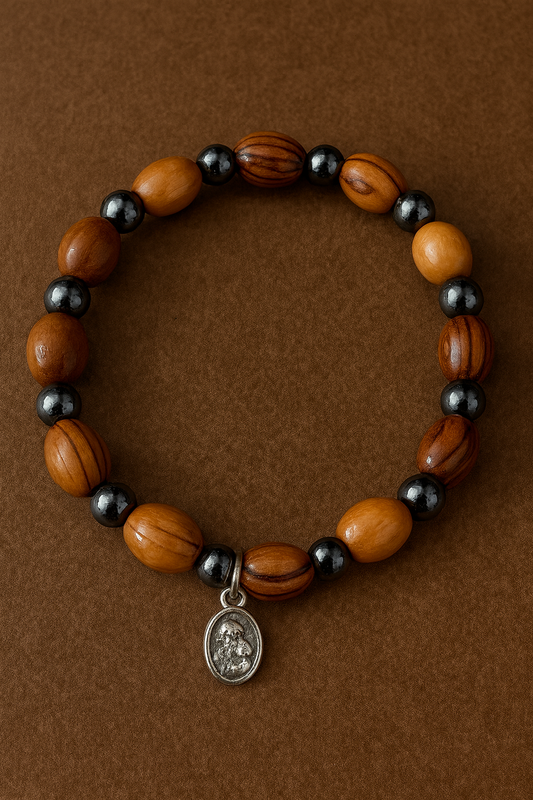 Wooden beaded bracelet with black beads and a silver charm on a brown background