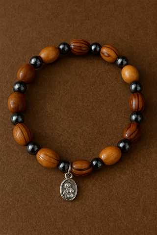 Wooden beaded bracelet with black beads and a silver charm on a brown background