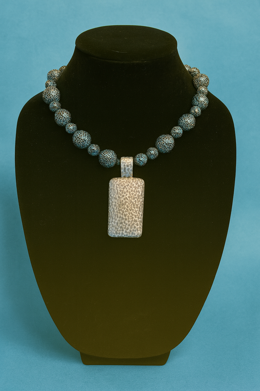 Necklace with a pendant on a black mannequin bust against a blue background