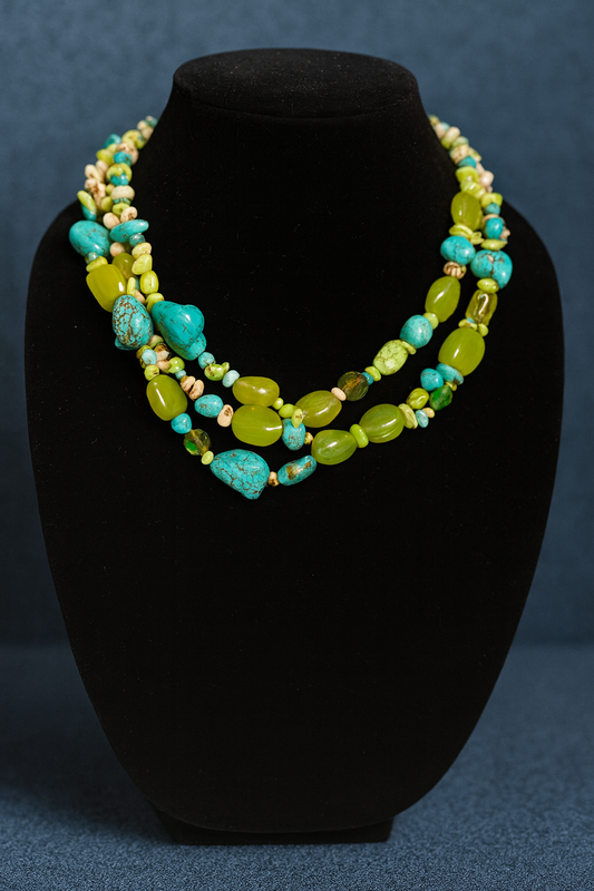 Necklace with turquoise and green beads on a black bust against a blue background