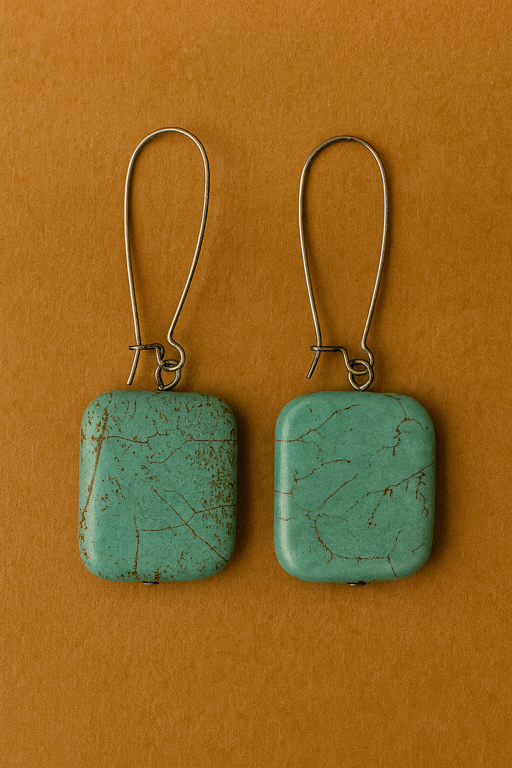 Pair of turquoise square earrings on a brown background