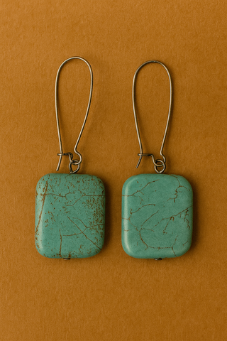 Pair of turquoise square earrings on a brown background